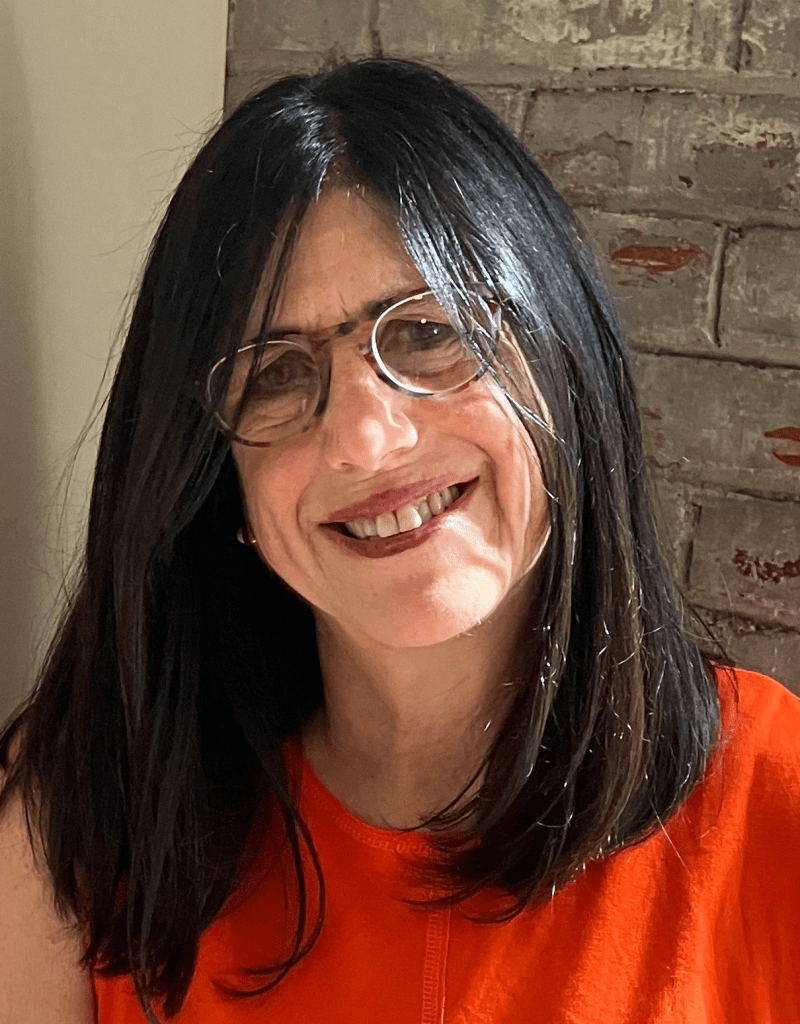 Julie headshot, woman in glasses with long dark hair and bright orange shirt
