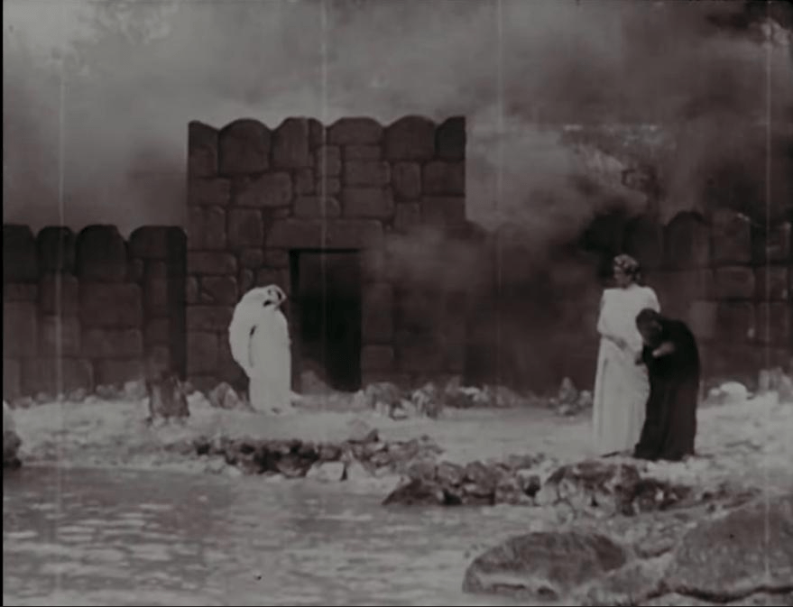 Black and white image. At least three figures on a riverbank. The scene at Dis Gate plays in full, with the Angel opening the gate.